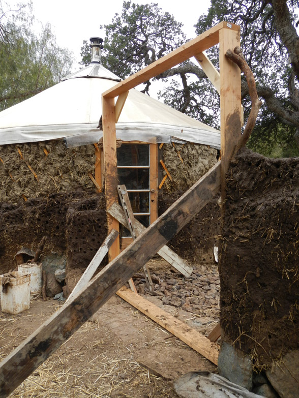 The door buck is braced from inside and outside to keep it level, while the cob walls set. We'll keep it in as long as we can. Clay shrinks as it dries, and it is expected that the cob walls will shrink a couple of inches and can potentially twist the door buck out of alignment.